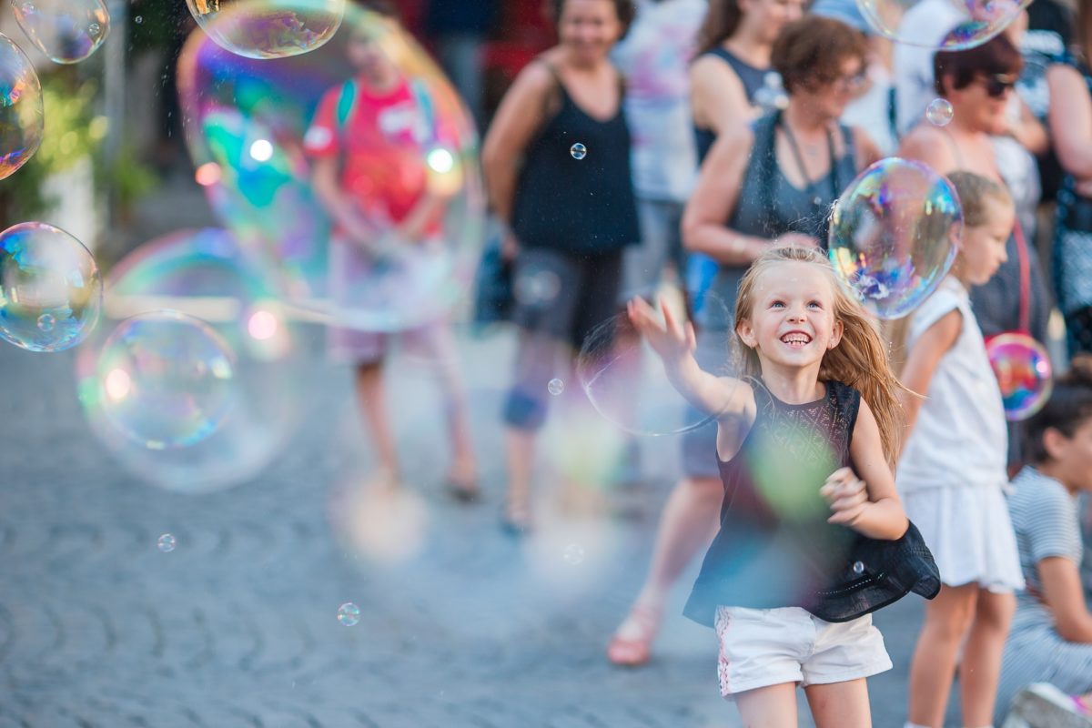 Adorable little girl blowing soap bubbles in Trastevere in Rome. Happy kid enjoy summer vacation in Italy