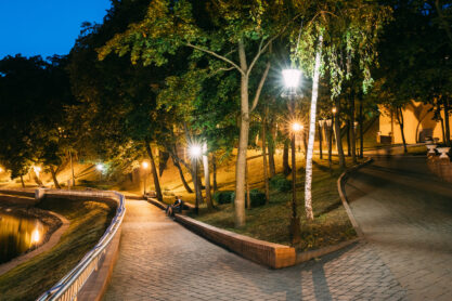 Gomel, Homiel, Belarus. Lighted Walkways Or Roads, Greenwood At Blue Hour Of Evening Or Night In City Park. Popular Place For Tourists And Locals In Gomel, Belarus.