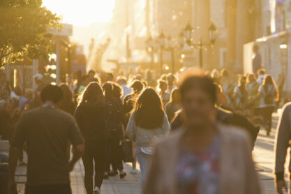 Silhouettes of people crowd walking down the street at summer evening, beautiful light at sunset, telephoto shot