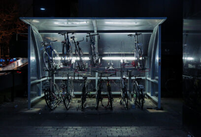 Bicycles In Illuminated Parking Lot At Night