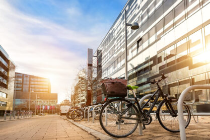 Bike parked near modern apartment residential buiding or college campus at downtown of european city street. Eco-friendly transport and healthy active lifestyle concept. Sustainable work commute.