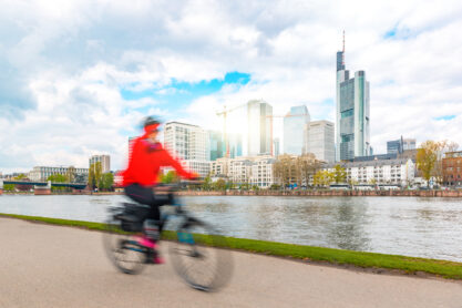 One person going by bike in Frankfurt, with financial downtown district on background - Sustainable commuting in the city, ecological transportation in Germany - Urban lifestyle concept