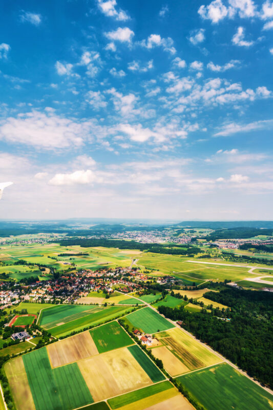 Swirzerland. Little towns and villages with green fields during the sunny day. Forest at the background. Cloudy sky