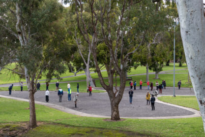 People playing pétanque, also called boules. It is winter, people playing at a public park wearing warm clothes. Group of aged people playing on the gravel. Adelaide, Australia