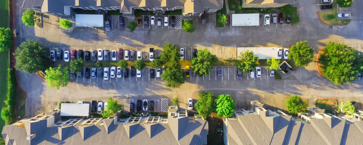 Panorama aerial view of apartment garage with full of covered parking, cars and green trees of multi-floor residential buildings in Houston, Texas, US. Urban infrastructure, transportation concept