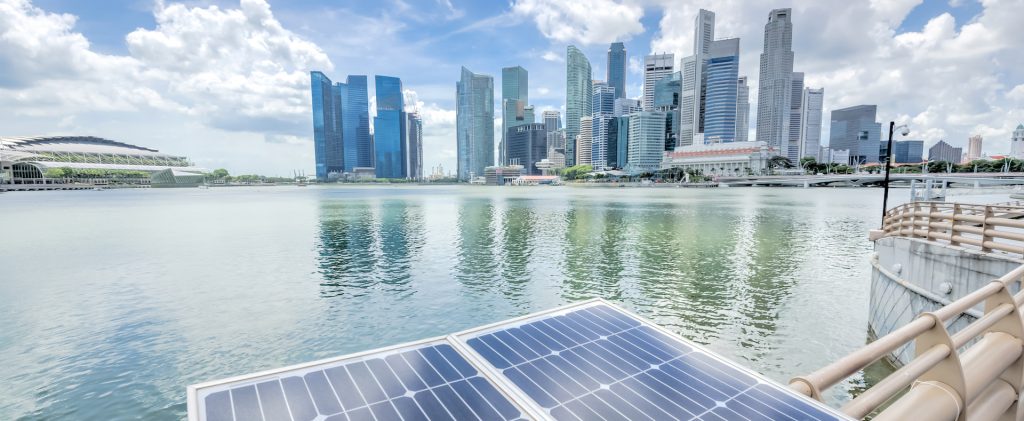 Panorama close-up solar panel with modern city and skyscrapers in background in Singapore. Cloud blue sky.
