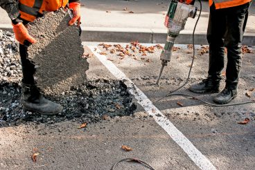 Workers remove a layer of old asphalt with a jackhammer on an autumn day. Construction work on the road.