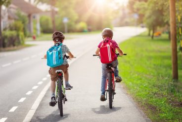 Two boys with backpacks on bicycles going to school. Concept of back to school.