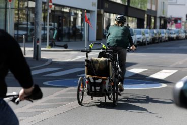 fahrradfahrer mit lastenfahrrad mit anhänger