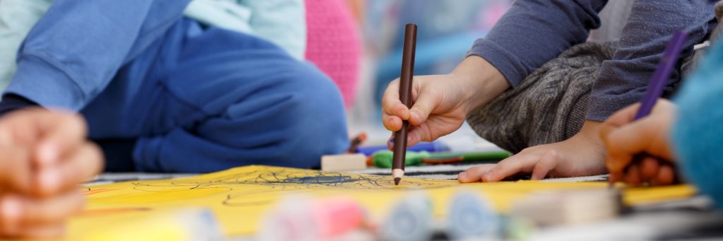 Little children drawing together with crayons at kindergarten