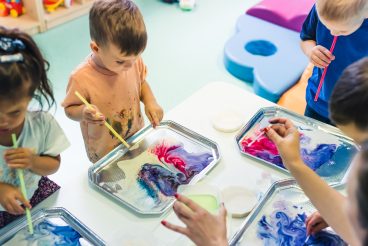 Multi-cultural nursery school. Toddlers playing with striped straws and milk painting, using nontoxic food coloring for colors. Creative kids activity for using their senses and brain development. Finger painting. High quality photo